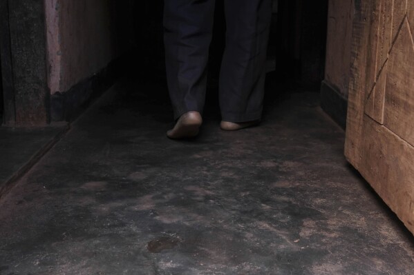Simon Tigawalana walks into his house with some clay-based earthen floors by EarthEnable on May 16, 2025, in Jinja, Uganda. (AP Photo/Hajarah Nalwadda)