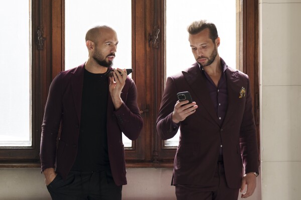 Andrew Tate, left, and his brother Tristan, right, wait at the Court of Appeals building in Bucharest, Romania, on Oct. 15, 2024. (AP Photo/Vadim Ghirda, File)
