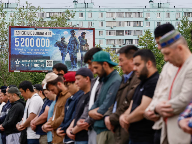 Muslims attend Eid al-Adha mass prayer, marking the end of the hajj pilgrimage, near a board promoting service in the Russian army and invites volunteers to sign a contract with the defence ministry, in Moscow, Russia June 6. REUTERS/Yulia Morozova