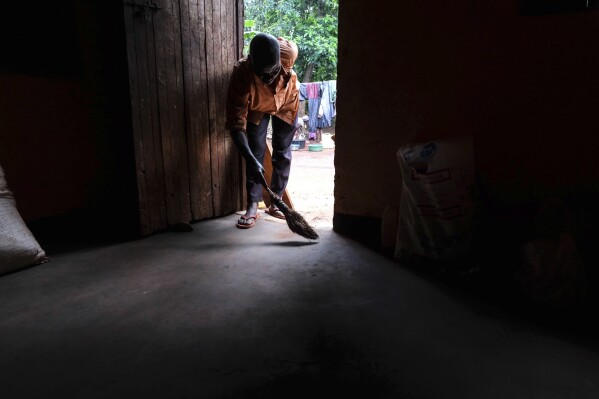 Simon Tigawalana sweeps his house with a clay-based earthen floor by EarthEnable on May 16, 2025, in Jinja, Uganda. (AP Photo/Hajarah Nalwadda)