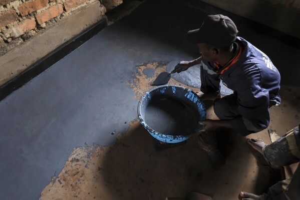Alex Wanda, a construction officer at EarthEnable, installs paste on floors May 17, 2025, in Jinja, Uganda. (AP Photo/Hajarah Nalwadda)
