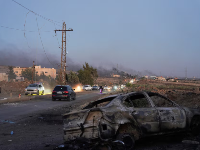 Smoke rises as a damaged car remains along a street, as Sweida province has been engulfed by nearly a week of violence triggered by clashes between Bedouin fighters and factions from the Druze, at Sweida governorate, Syria, July 18, 2025. REUTERS/Karam al-Masri