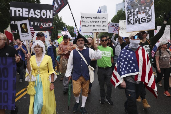 Demonstrators dressed in Revolutionary War era clothing march down Benjamin Franklin Parkway during the
