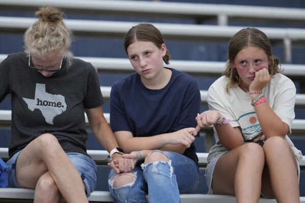 Attendees hold hands during a vigil for flooding victims at Tivy Antler Stadium on Wednesday, July 9, 2025, in Kerrville, Texas. (AP Photo/Ashley Landis)