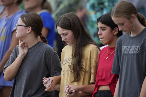 Attendees hold hands during a vigil for flooding victims at Tivy Antler Stadium on Wednesday, July 9, 2025, in Kerrville, Texas. (AP Photo/Ashley Landis)