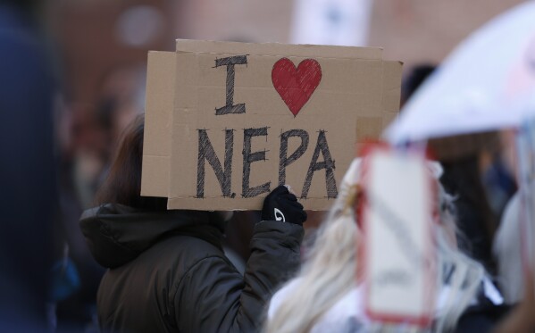 Joan Lutz, of Boulder, Colo., waves a placard at a rally of advocates to voice opposition to efforts by the Trump administration to weaken the National Environmental Policy Act, which is the country's bedrock law aimed at protecting the environment, on Feb. 11, 2020, in Denver. (AP Photo/David Zalubowski)
